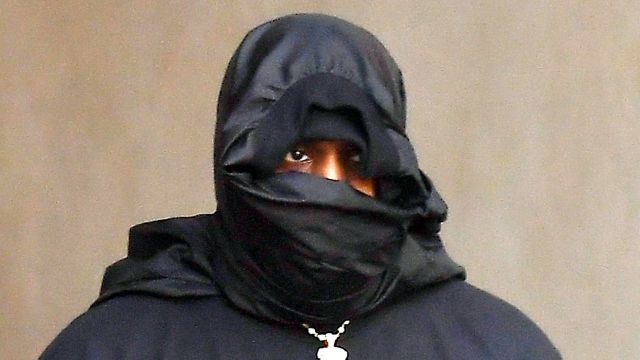 Kanye West covers his face with black balaclava as he signs